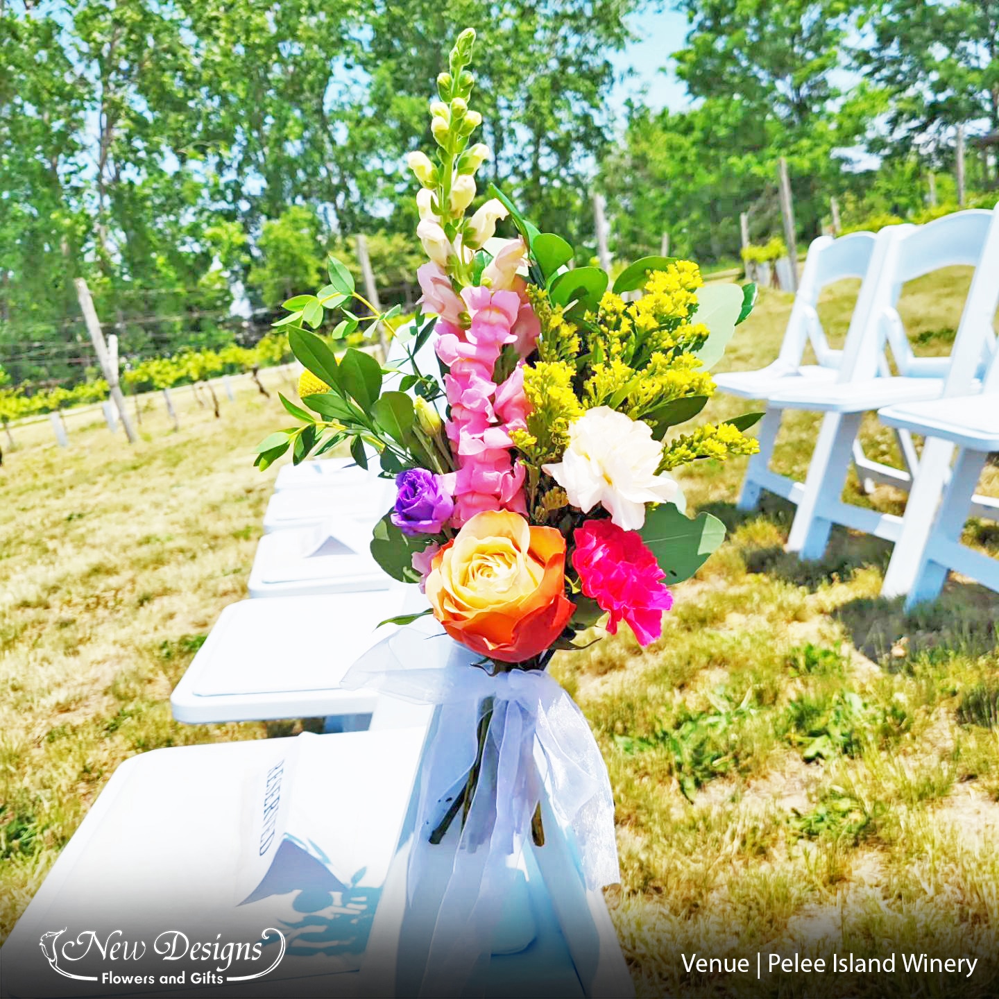 A close up of an aisleway Chair Floral Installment, with Yellow and Orange Roses, Deep Pink Carnations, Peach Carnations, Bright Pink Snap Dragons, Deep Purple Lisianthus, Bright Yellow Solidago and mixed Deep and Light Greenery